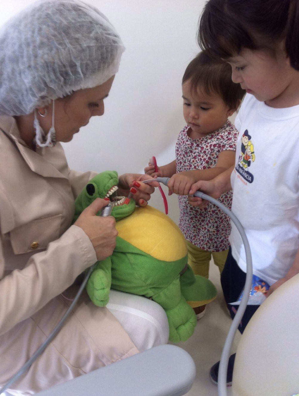 Crianças participando do atendimento com boneco de pelúcia no consultório