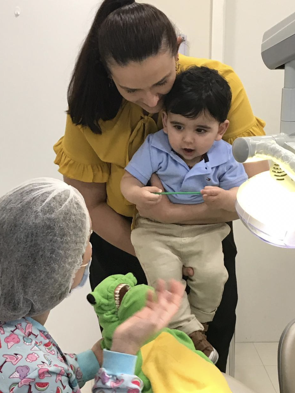 Bebê no colo da mãe recebendo primeira avaliação odontológica