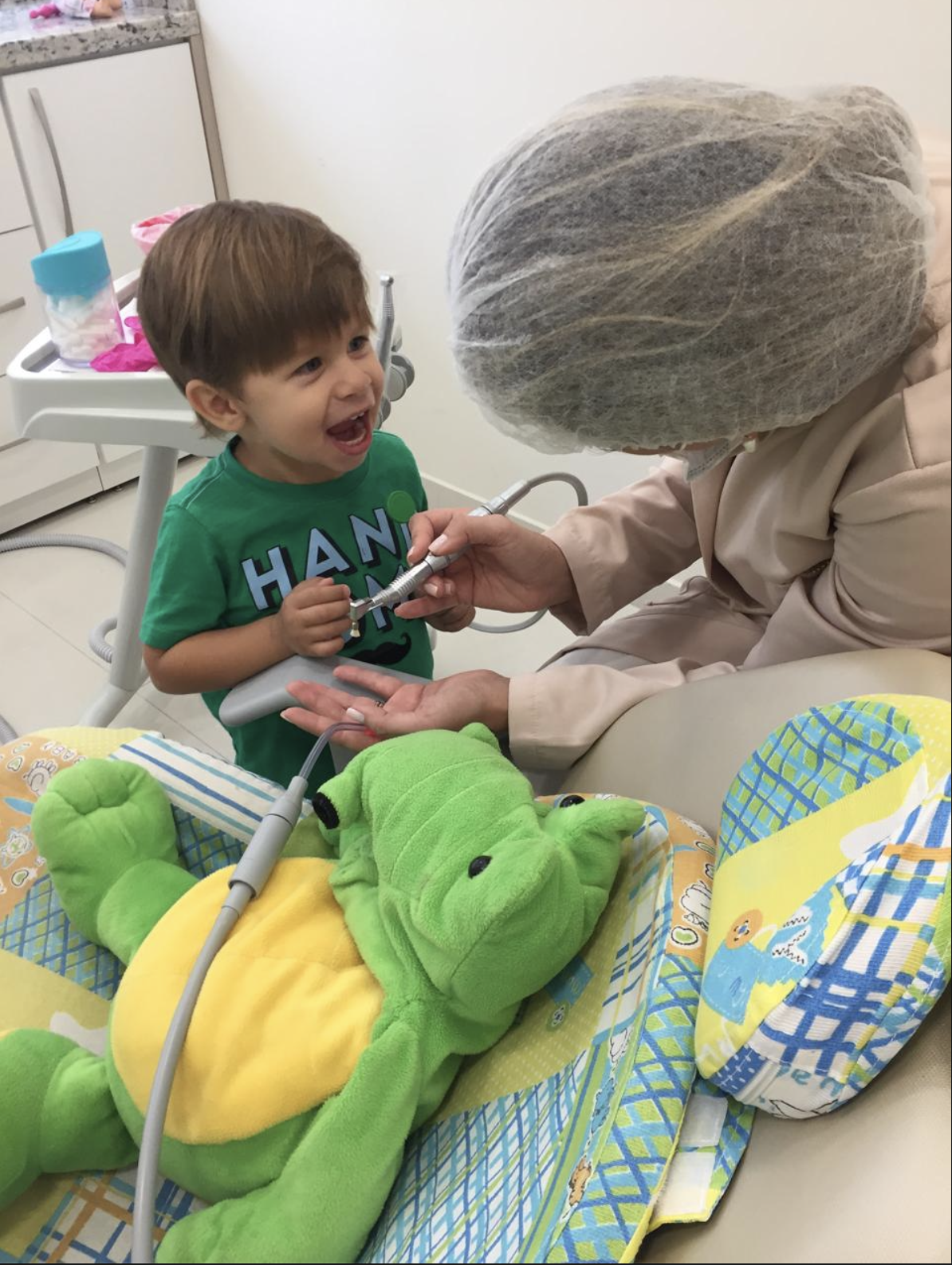 Criança sorrindo enquanto conhece os instrumentos da consulta odontológica
